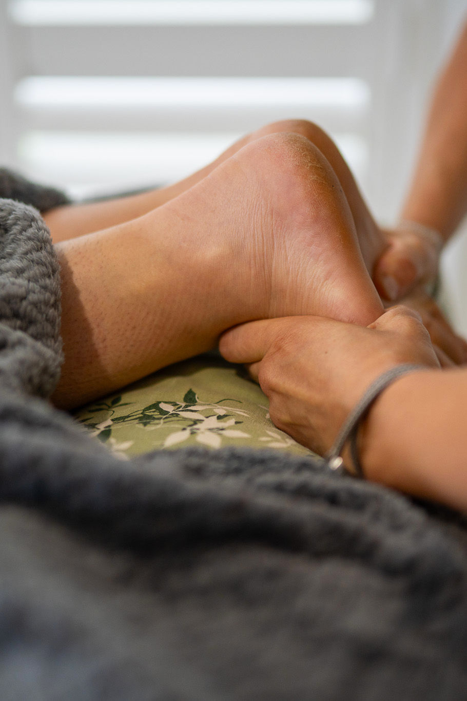 The therapist's hands are massaging the patients feet, the patient is laying down.